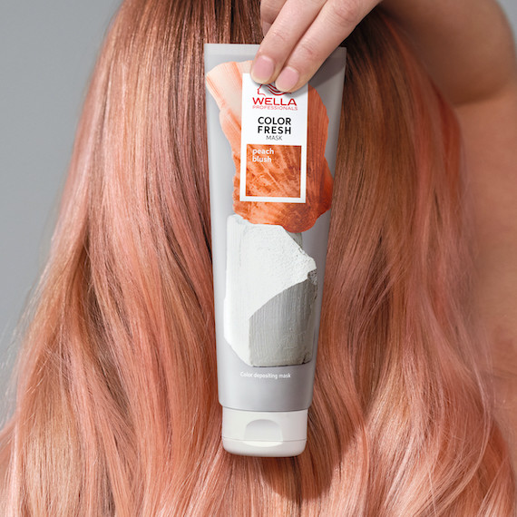 Model with peach blonde hair holds up Color Fresh Mask in Peach Blush.