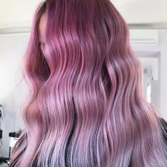 Headshot of a person who's face is mostly concealed by their long, pink-purple wavy hair