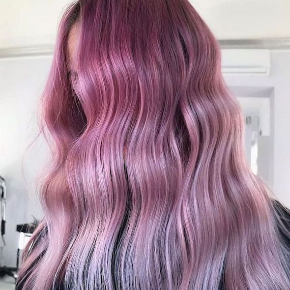 Side profile of model with long, wavy hair, featuring a fuchsia to pastel pink ombre.