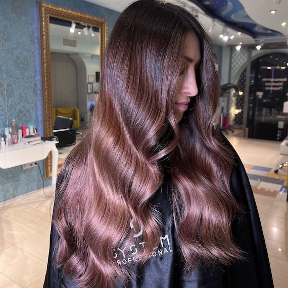 Model looks to the side to show off long, brunette and rose brown ombre hair.