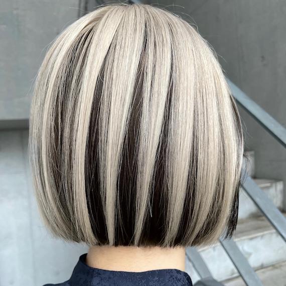 Back of model’s head with black bob haircut and chunky platinum highlights.
