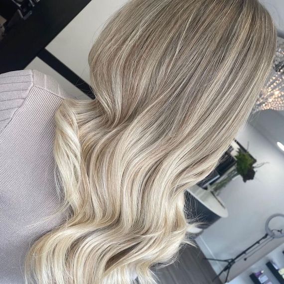 Back of model’s head with long, loosely curled hair in platinum ombre tones.