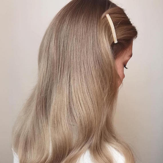 Side profile of woman with glossy blonde hair, created using Wella Professionals.