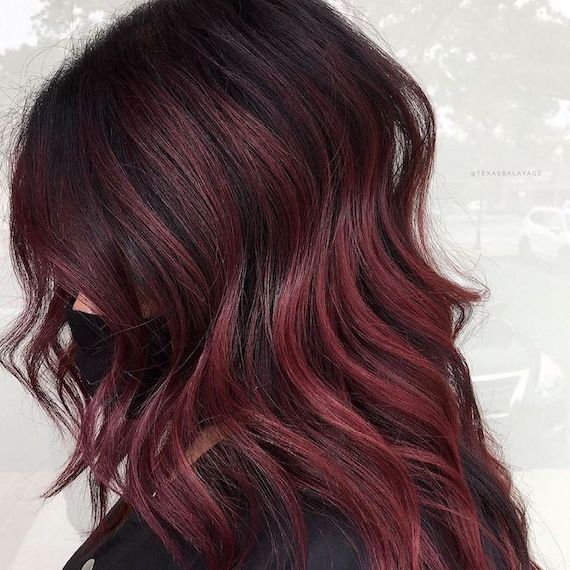 Headshot of a person facing side-on showing just their dark, purple, burgundy hair.