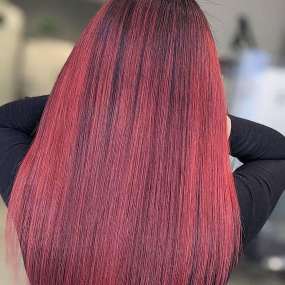Back of a person’s head reveals their long, straight chili red highlights on black hair, coloured using products by Wella Professionals.