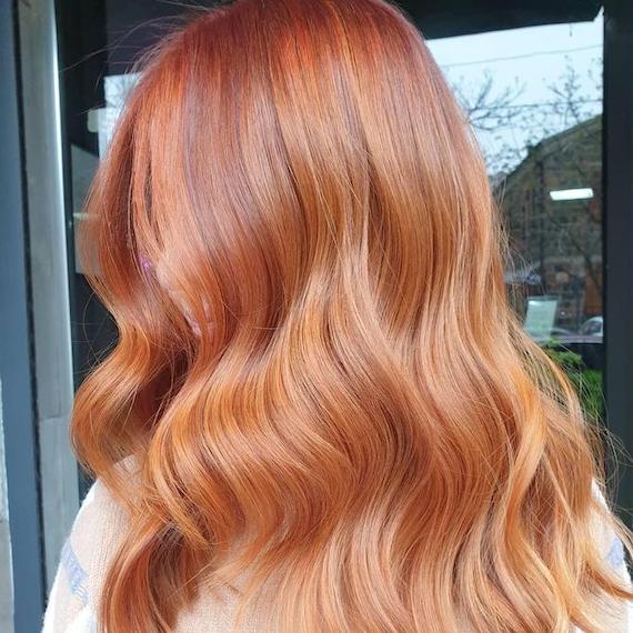 Side profile of person with long, wavy, copper coloured hair.