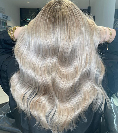 Silver blonde wavy hair that’s been colored and styled using a hair repair formula by Wella Professionals