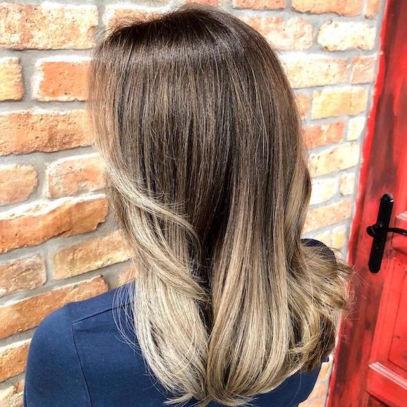 Frau mit aschblondem Ombré und dunklem Haaransatz, kreiert mit Wella Professionals.