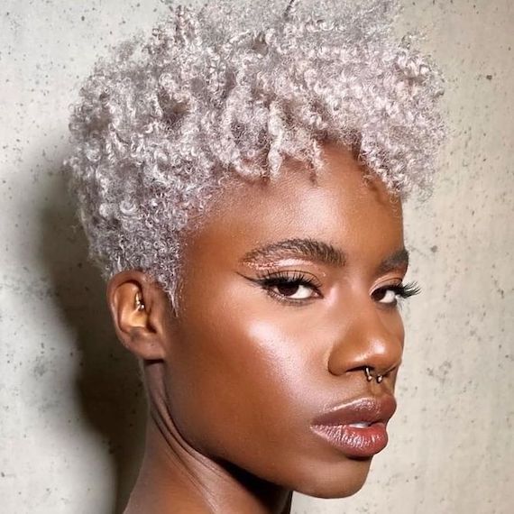 Model with short, icy blonde hair, featuring an undercut and tight, bouncy curls on top.