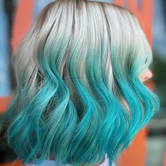 Side profile of model with platinum blonde bob haircut featuring mint green ombre through the mid-lengths and ends.