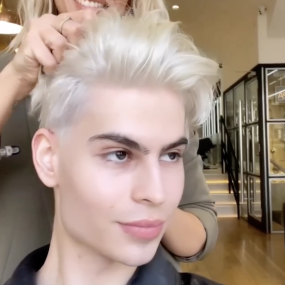 Model with cool blonde hair styled in a short pompadour haircut.