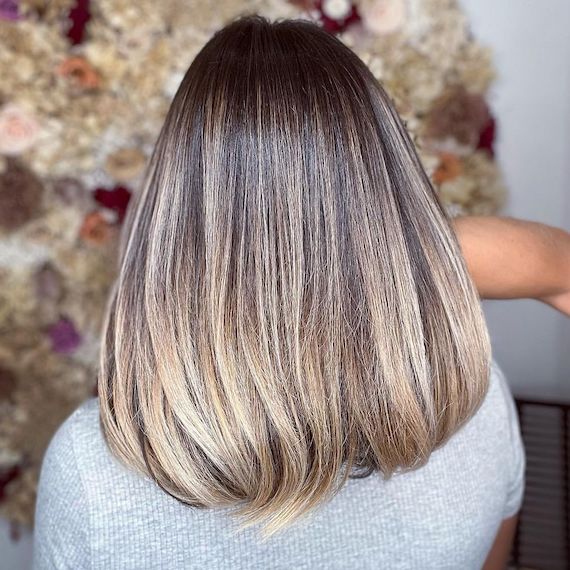 Model with shoulder-length, straight, sleek, brown hair and a cool, ashy blonde ombre.