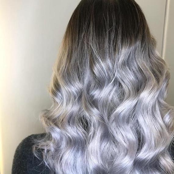 Back of woman’s head with long, curly, silver grey balayage, created using Wella Professionals.
