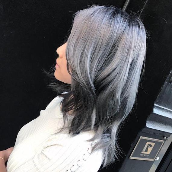 Side profile of woman with wavy, silver reverse balayage, created using Wella Professionals.