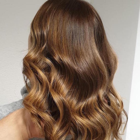 Back of woman’s head with wavy, light brown sombre hair, created using Wella Professionals.