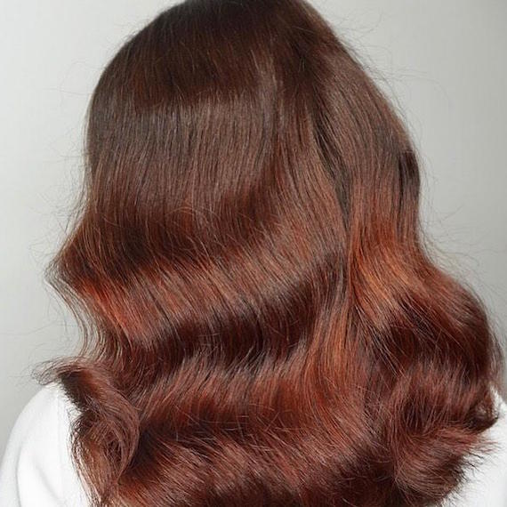Back of woman’s head with loosely curly, burgundy sombre hair, created using Wella Professionals.