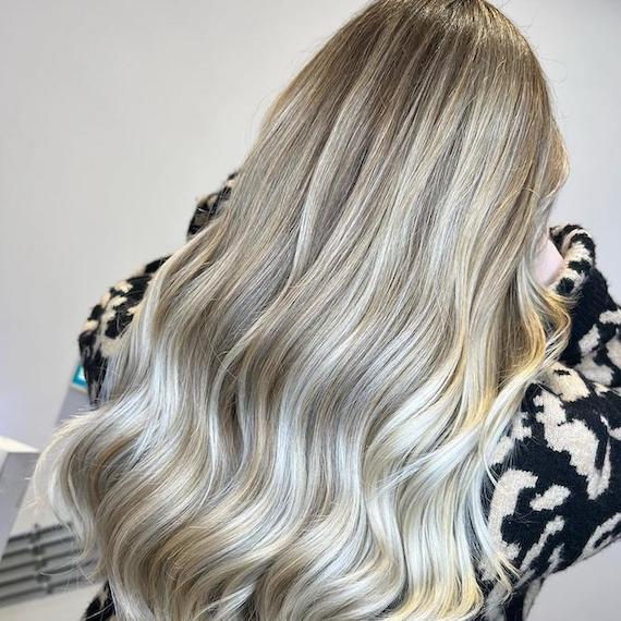 Back of woman’s head with long, wavy, ash and stone blonde hair.