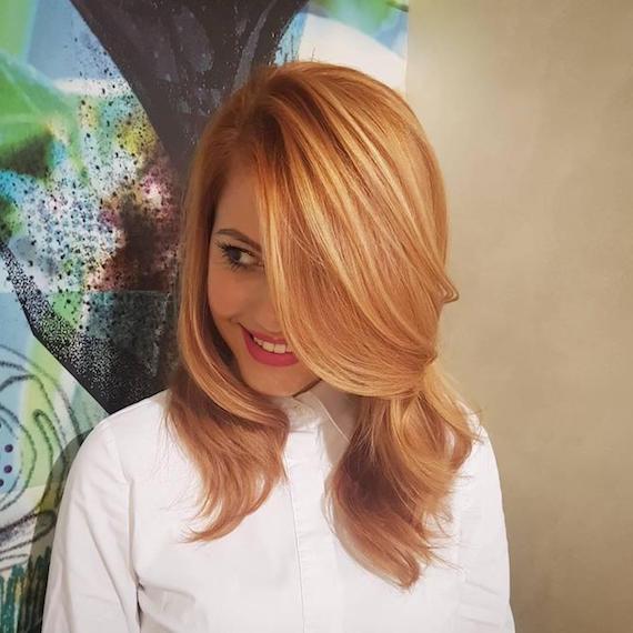 Frau mit weißem Hemd und erdbeerblonden Strähnchen, kreiert mit Wella Professionals.