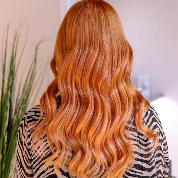 Der Hinterkopf einer Frau zeigt langes, gewelltes, erdbeerblondes Ombré, das mit Wella Professionals kreiert wurde.