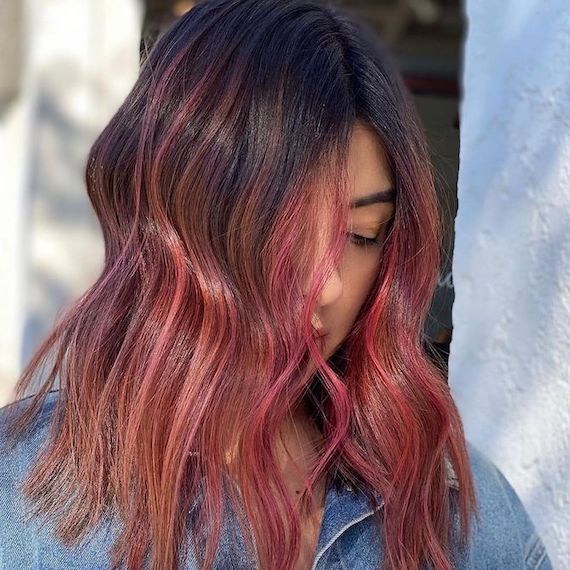Side profile of model with mid-length brown hair and vibrant strawberry balayage.