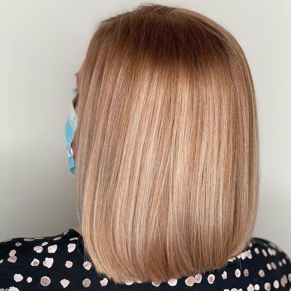Back of woman’s head with amber blonde hair and retouched roots, created using Wella Professionals.