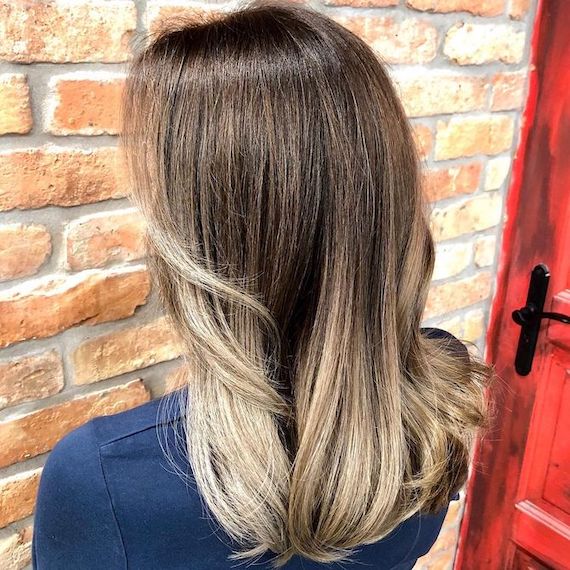Back of woman’s head with ash brown roots and ash blonde balayage, created using Wella Professionals.
