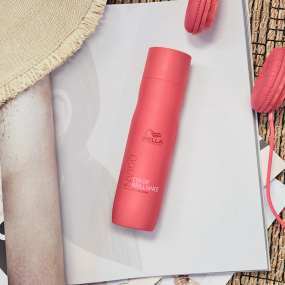 Eine Flasche INVIGO Color Brilliance Color Protection Shampoos, die auf einer Zeitschrift liegt.