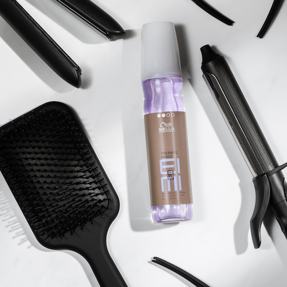 Eine Flasche EIMI Thermal Image, umgeben von Haarstyling-Tools.