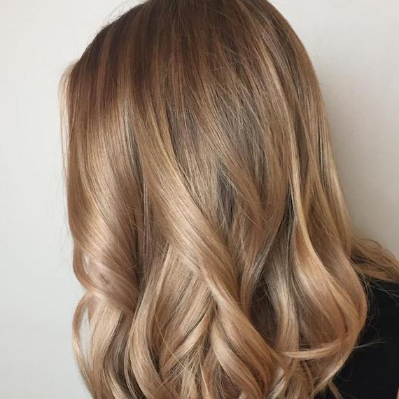 Side profile of model with long, warm blonde hair and subtle highlights, created using Wella Professionals.
