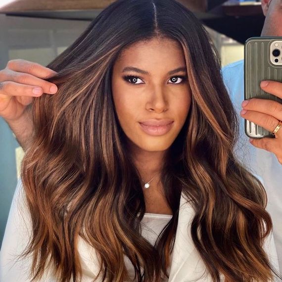 Model facing camera with dark brown hair and bronze balayage.