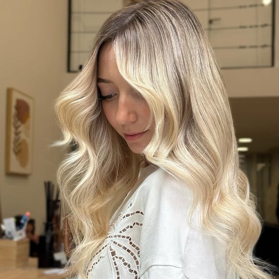 Model with long, loosely curled, blonde hair with an expensive-looking glow.