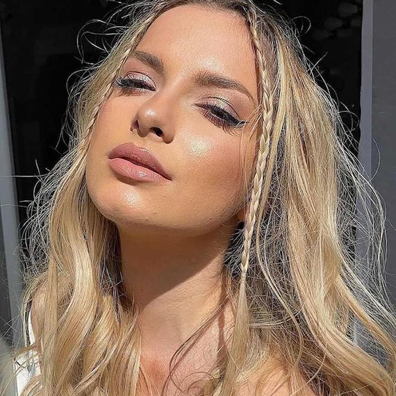 Model with long, tousled, honey blonde hair featuring micro braids through the front.