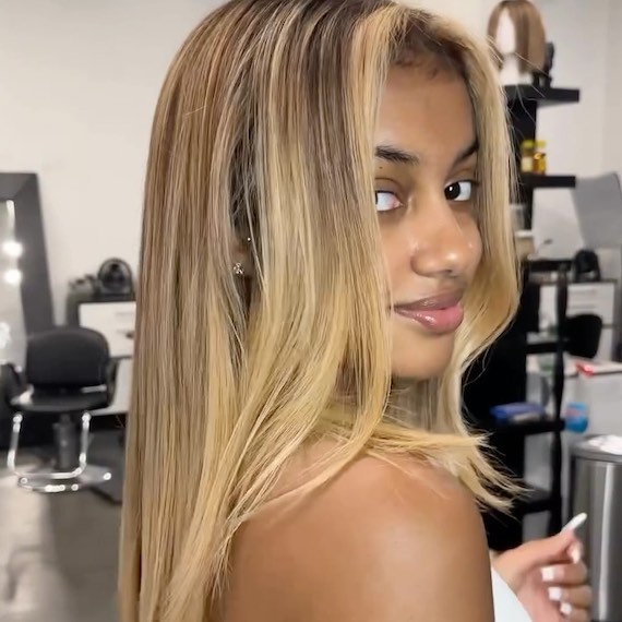 Model with vanilla blonde highlights through long, dark hair.