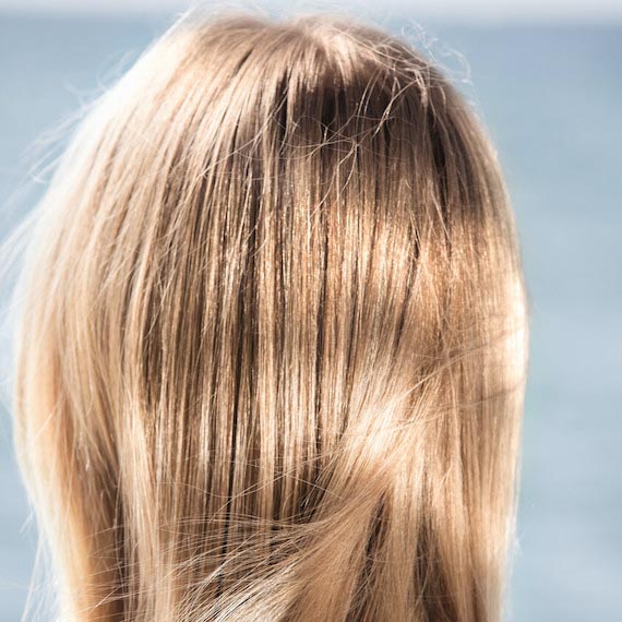Close-up of a model’s blonde hair with the sun beaming down.