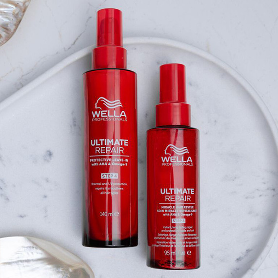 Two bottles of ULTIMATE REPAIR Protective Leave-In on a marble surface.