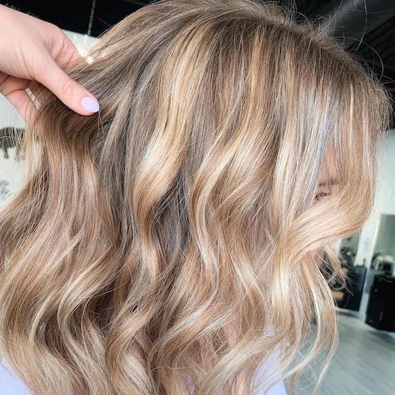 Side profile of woman with honey blonde, long bob haircut, created using Wella Professionals.