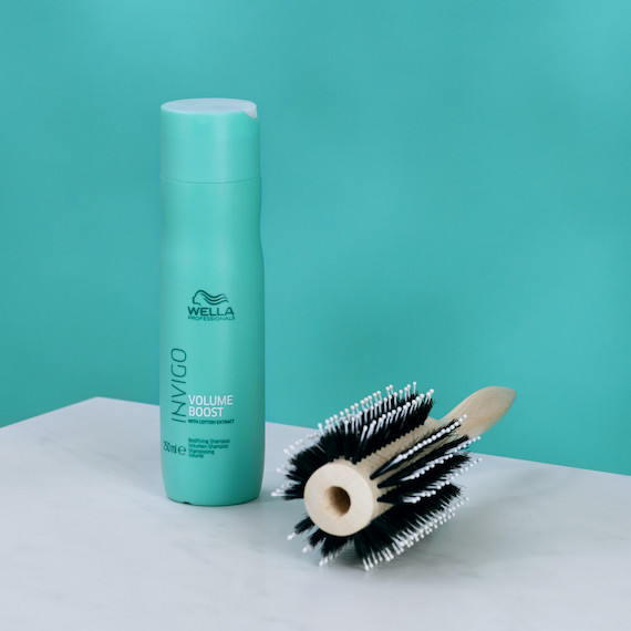 INVIGO Volume Boost Bodifying Shampoo next to a large round brush.