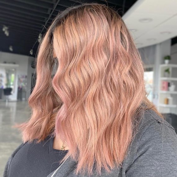 Model with mid-length, wavy hair in a peachy vanilla blonde shade.