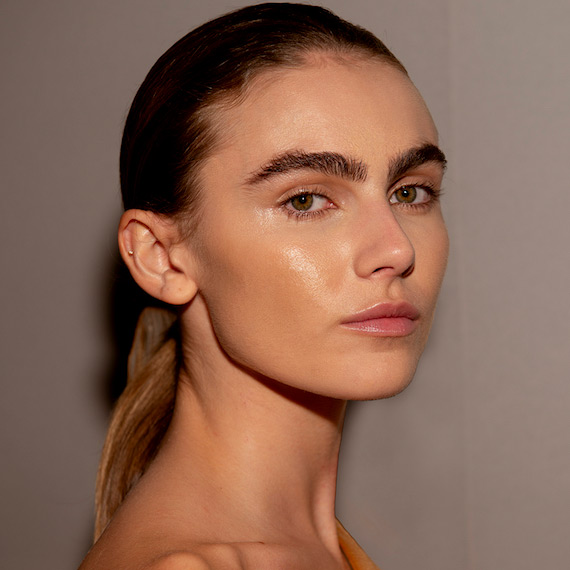 A model with long, blonde hair secured in a low, sleek ponytail.