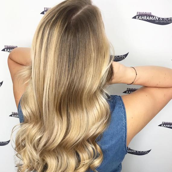 Foto, das den Hinterkopf eines Models mit langen, gewellten, warmblonden Haaren zeigt. Kreiert mit Wella Professionals.