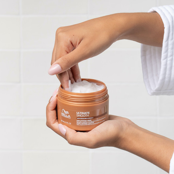 Model scoops out ULTIMATE SMOOTH Mask from the tub.