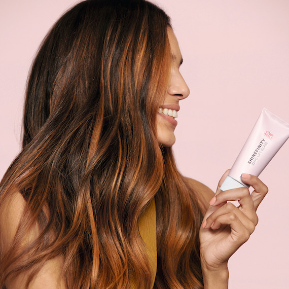 Image of woman holding a Shinefinity hair Glaze by Wella Professionals