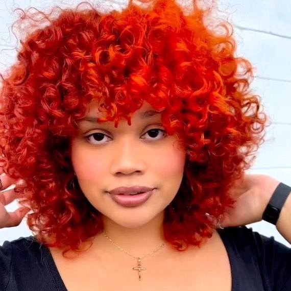 Model with curly, orange and cherry red hair.