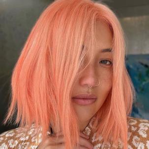 Model with shoulder-length bob haircut in a bright peach blonde shade.
