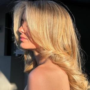 Sun shines on model’s honey blonde, glossy hair. 