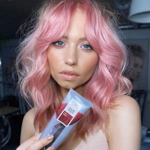 Model with wavy, candy pink hair holds up Color Fresh Mask in Rose Blaze.