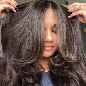Model runs their hands through their long, dark brown, glossy hair.