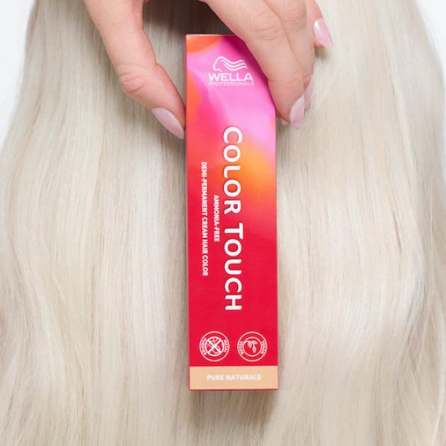 Model with icy blonde hair holds up a box of Color Touch. 