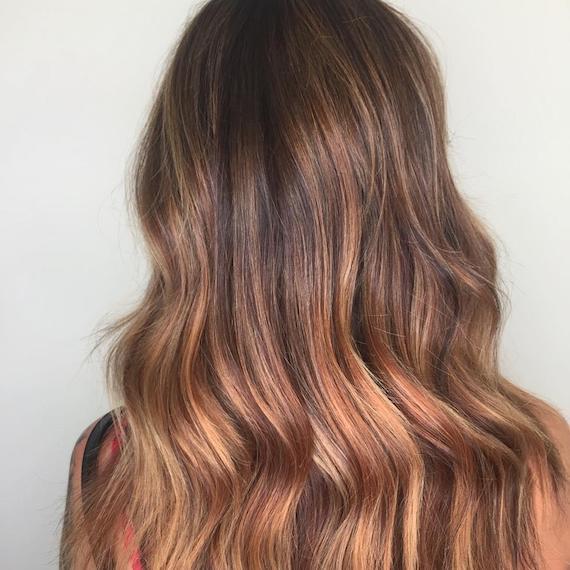 Model with long, wavy hair and soft balayage, created using Wella Professionals.