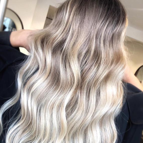 Model with long, wavy hair and ice blonde balayage, created using Wella Professionals.